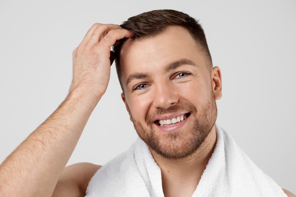 Der Patient, der eine Haartransplantation hatte, streichelt sein Haar.