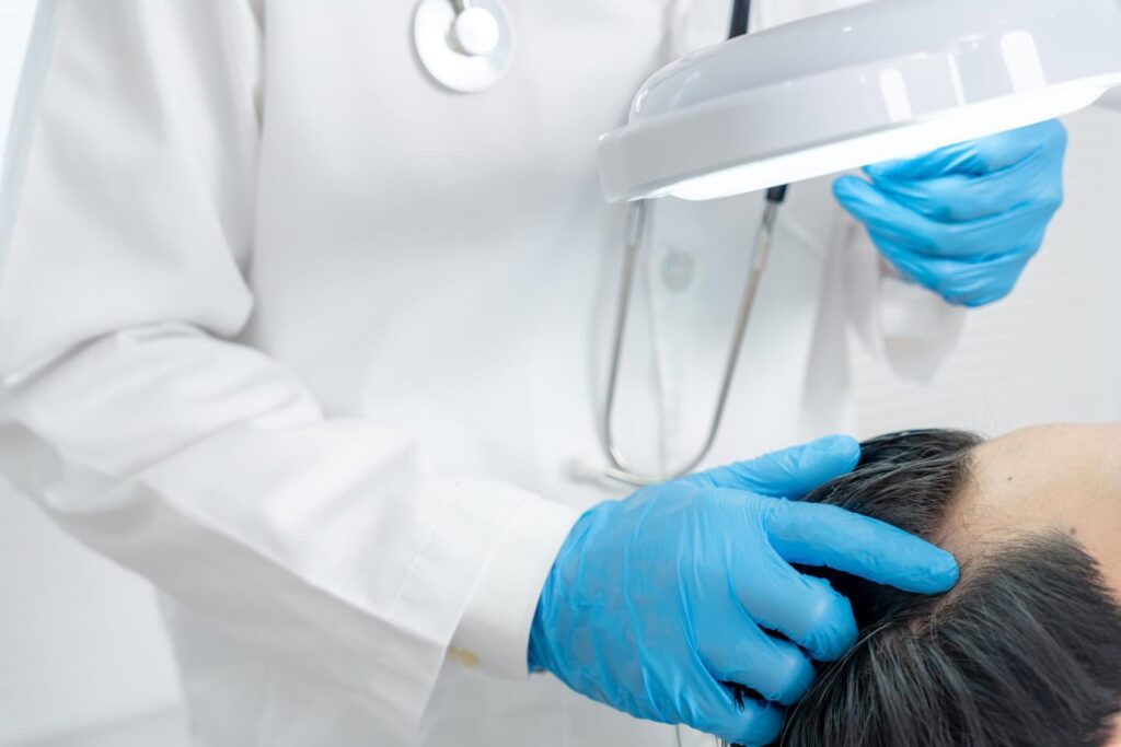 Der Arzt untersucht die Anzeichen von Haarausfall bei der Patientin.