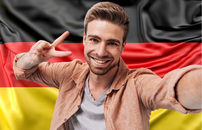 Ein männlicher Patient, der in Deutschland eine Haartransplantation durchgeführt hat, lächelt vor der deutschen Flagge 2